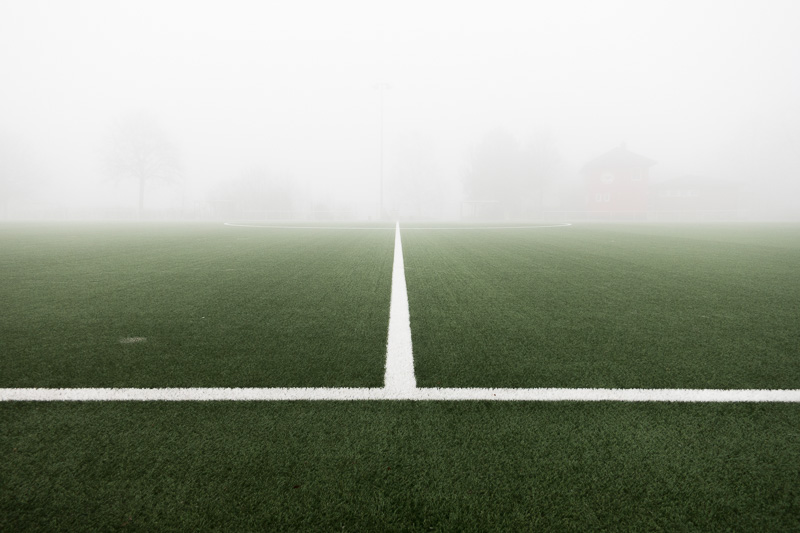 Mittellinie auf einem Fussballplatz mit Nebel