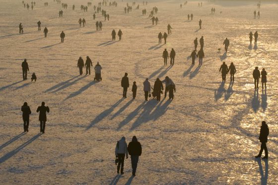 Menschenmenge auf zugefrorenen See im Abendlicht