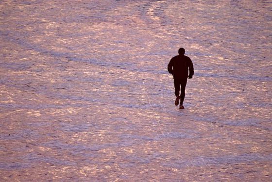 Jogger im Winter auf zugefrorenen See im Abendlicht